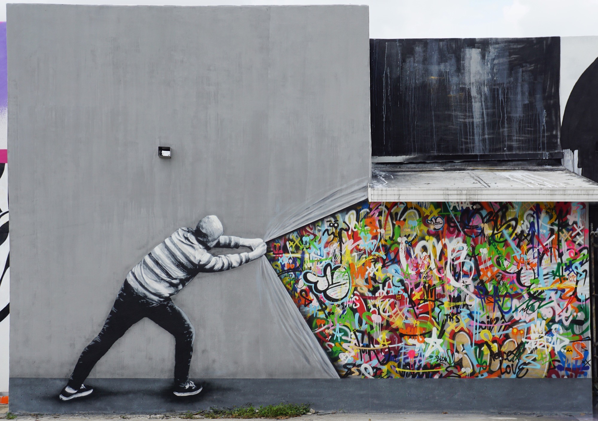 Street art of multicolored graffiti behind a grey building facade. 